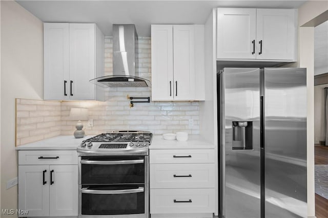 kitchen with backsplash, appliances with stainless steel finishes, white cabinetry, and wall chimney exhaust hood