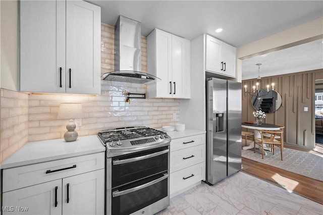 kitchen with stainless steel appliances, wall chimney exhaust hood, white cabinets, and light countertops