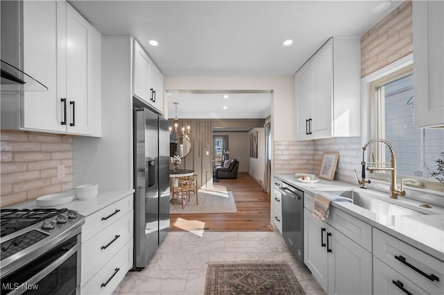 kitchen with a chandelier, light countertops, marble finish floor, stainless steel appliances, and a sink