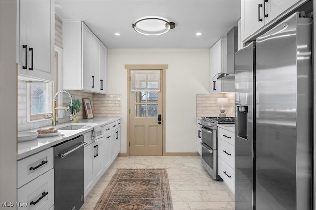 kitchen with wall chimney range hood, plenty of natural light, marble finish floor, stainless steel appliances, and a sink