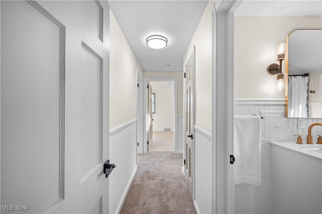 hallway with carpet flooring and a sink