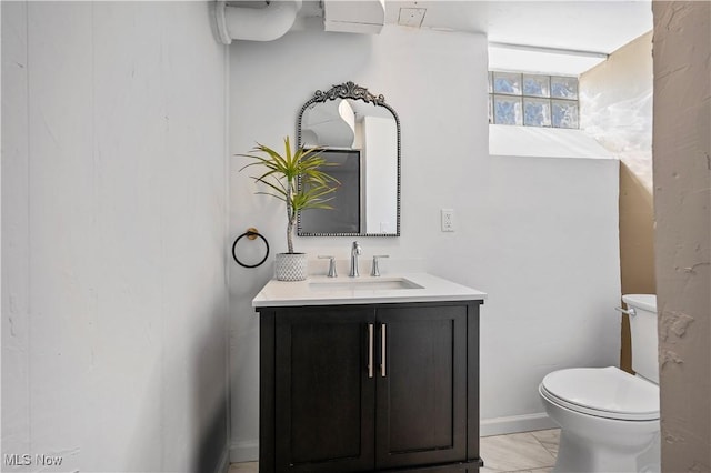 bathroom with toilet, marble finish floor, and vanity