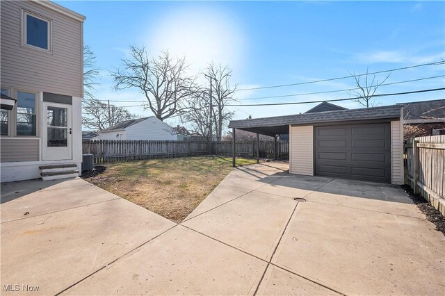 detached garage with a carport, central air condition unit, driveway, and fence