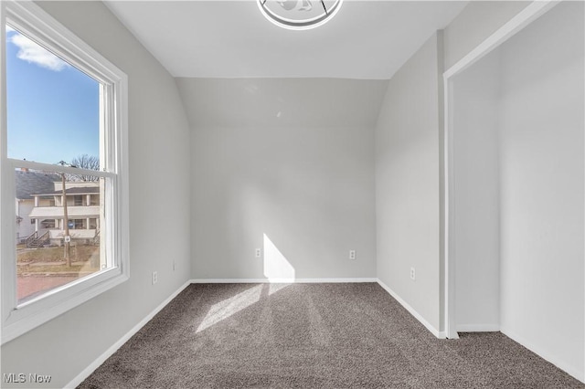 spare room with baseboards, lofted ceiling, and carpet