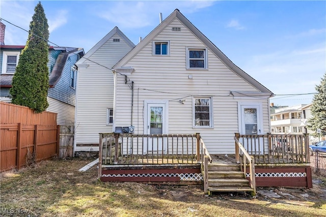 back of property with a deck and fence