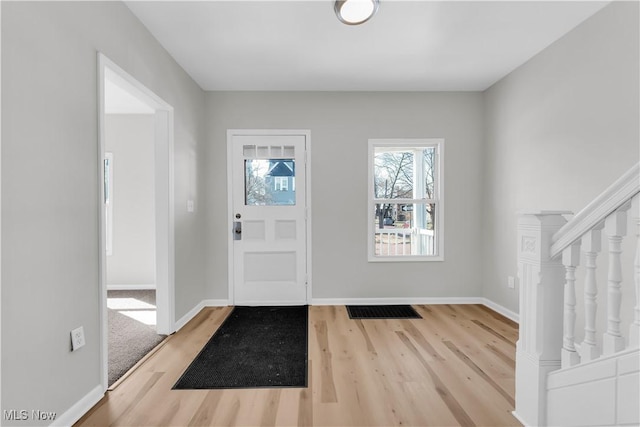 entryway with stairs, wood finished floors, visible vents, and baseboards