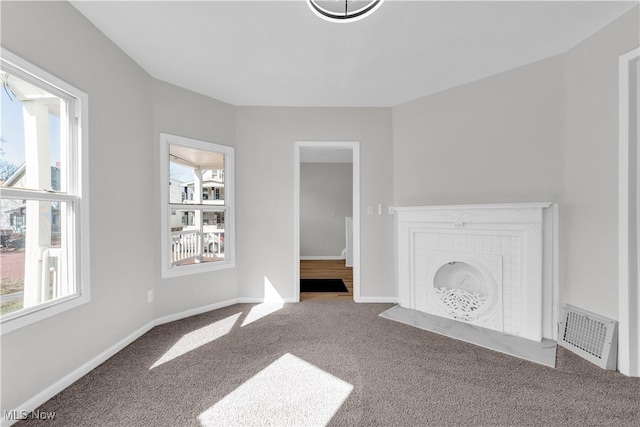 unfurnished living room featuring a wealth of natural light, visible vents, carpet, and a tile fireplace