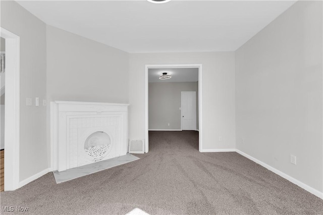 unfurnished living room with visible vents, a brick fireplace, baseboards, and carpet floors