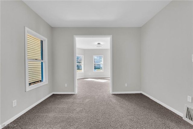 carpeted spare room featuring visible vents and baseboards