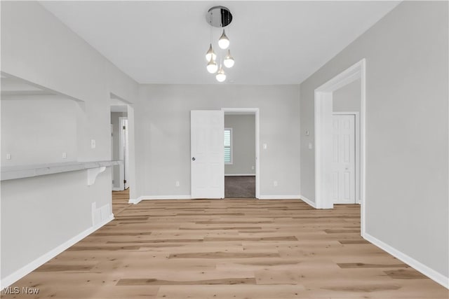 unfurnished dining area featuring light wood-type flooring and baseboards