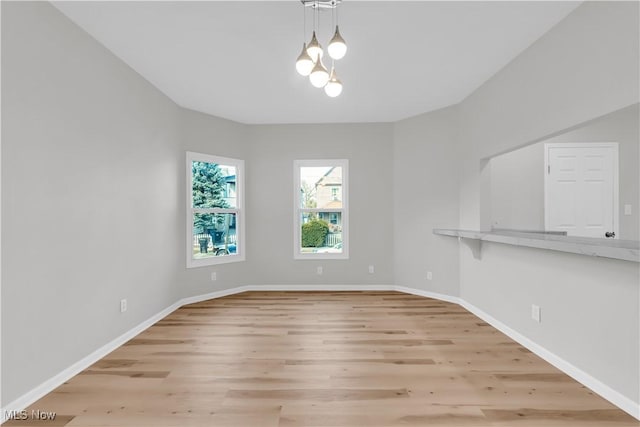 unfurnished room with baseboards and light wood-type flooring