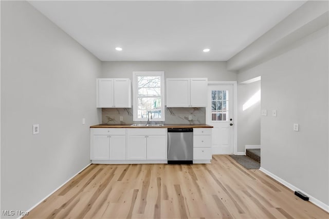 kitchen with decorative backsplash, white cabinetry, dishwasher, and butcher block counters