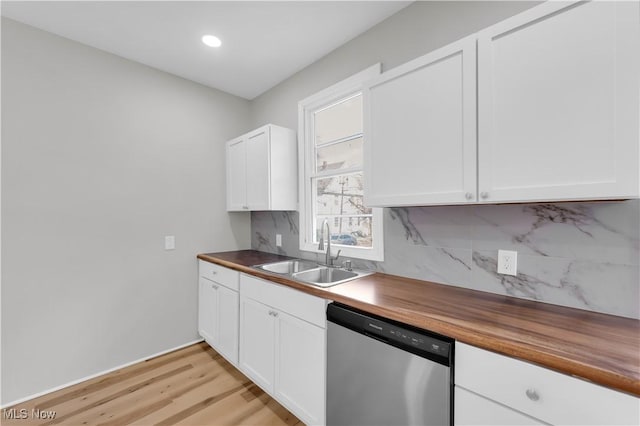 kitchen with white cabinetry, a sink, stainless steel dishwasher, backsplash, and butcher block counters