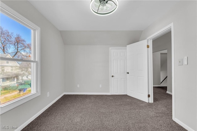 interior space with baseboards, carpet, and vaulted ceiling