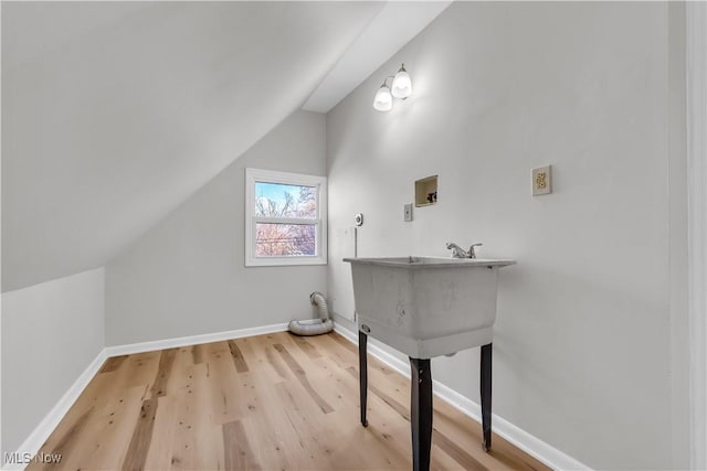 bathroom featuring baseboards, lofted ceiling, and wood finished floors