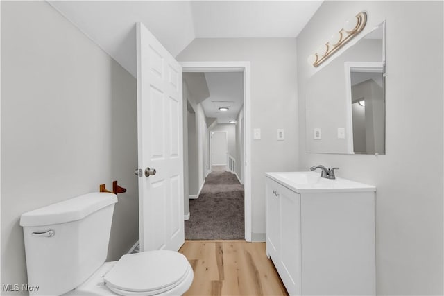 half bath featuring toilet, vanity, and wood finished floors