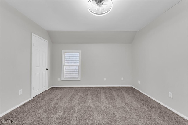 unfurnished room with carpet flooring, baseboards, and vaulted ceiling