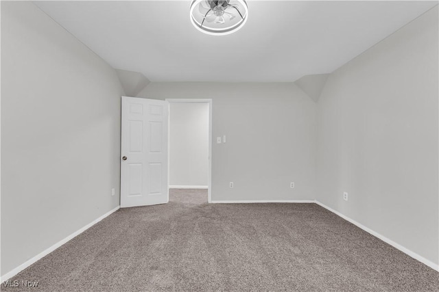 unfurnished room featuring baseboards, carpet, and vaulted ceiling