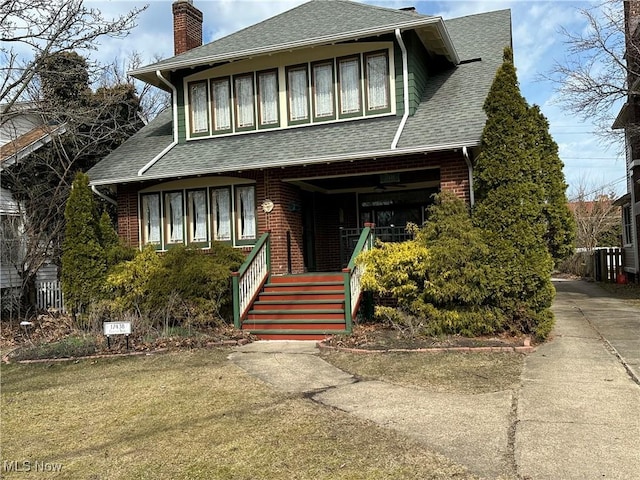 view of front facade with brick siding, roof with shingles, and a chimney