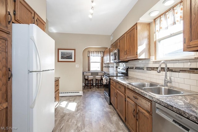 kitchen with a baseboard heating unit, brown cabinets, appliances with stainless steel finishes, and a sink