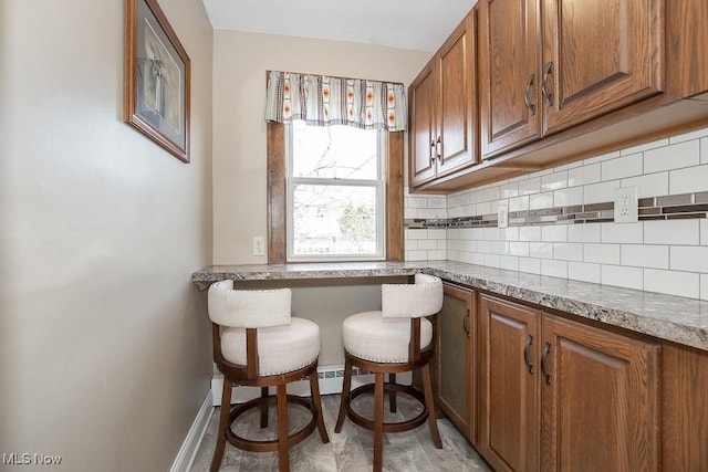 kitchen featuring tasteful backsplash, brown cabinets, and baseboards