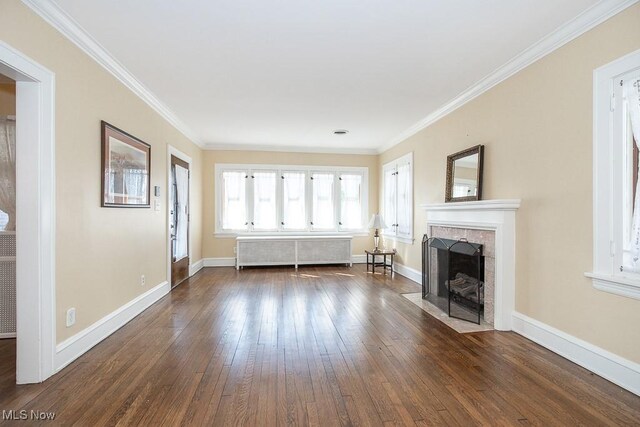 unfurnished living room featuring a tile fireplace, radiator, baseboards, and hardwood / wood-style flooring