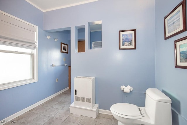 bathroom with heating unit, baseboards, crown molding, tile patterned floors, and toilet