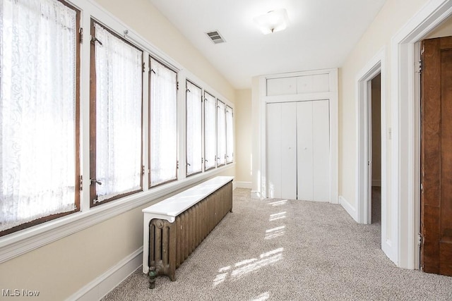 hall featuring visible vents, baseboards, and carpet