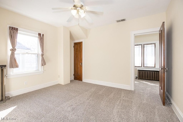 unfurnished bedroom with visible vents, carpet flooring, radiator heating unit, and baseboards