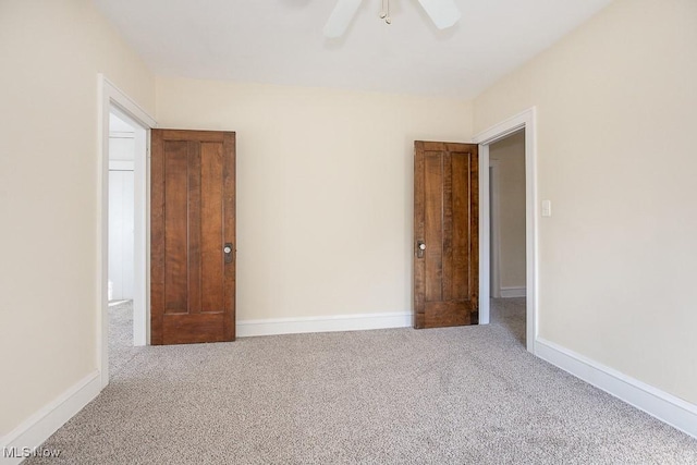 carpeted empty room featuring ceiling fan and baseboards