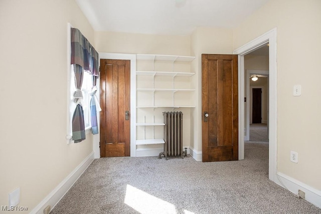 unfurnished bedroom with a closet, baseboards, radiator, and carpet flooring