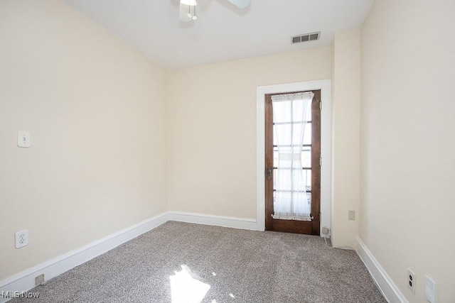 carpeted empty room featuring baseboards, visible vents, and ceiling fan