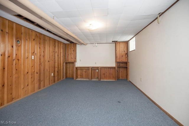 basement featuring wood walls and carpet