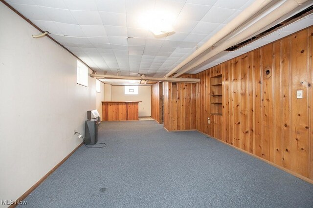 below grade area featuring wooden walls, baseboards, and carpet floors