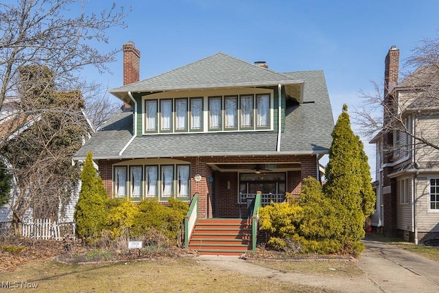 view of front of property with brick siding, roof with shingles, and a chimney