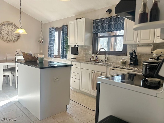 kitchen featuring backsplash, decorative light fixtures, vaulted ceiling, white cabinets, and a sink