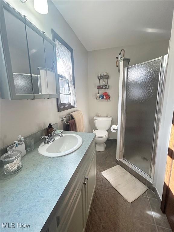 bathroom featuring vanity, toilet, a shower stall, and tile patterned flooring