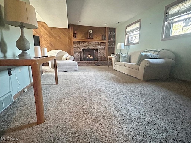 carpeted living area featuring wooden walls, visible vents, a fireplace, and built in shelves