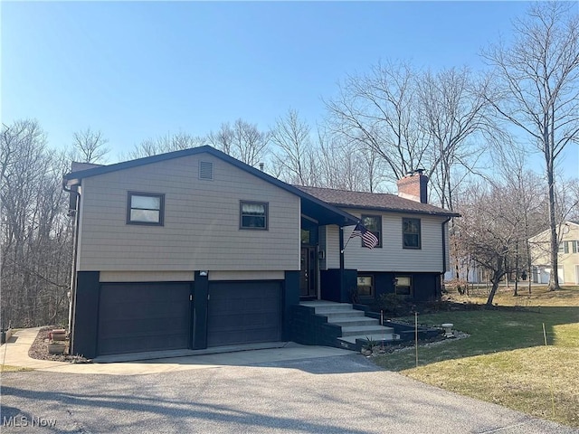 split foyer home featuring a chimney, a front lawn, aphalt driveway, and a garage