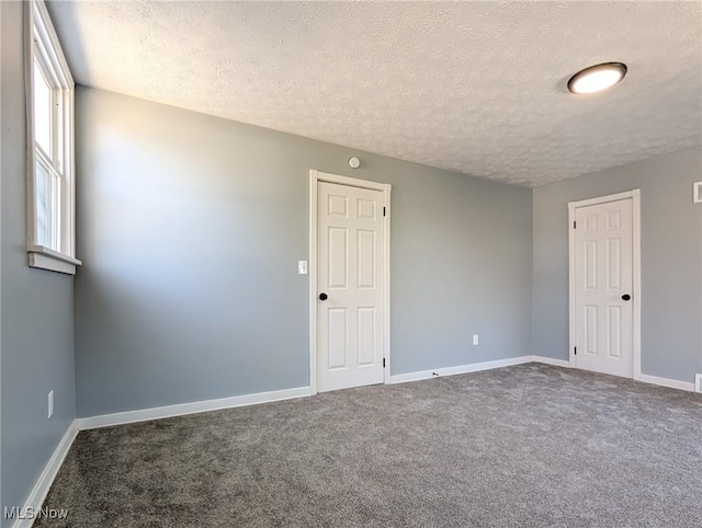 carpeted empty room with a textured ceiling and baseboards