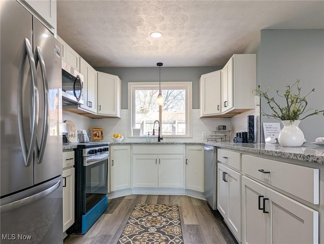 kitchen featuring a sink, dark wood finished floors, white cabinetry, stainless steel appliances, and decorative backsplash