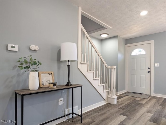 entrance foyer with visible vents, baseboards, a textured ceiling, and wood finished floors