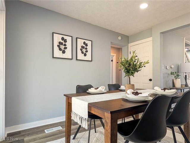 dining room featuring visible vents, baseboards, and wood finished floors