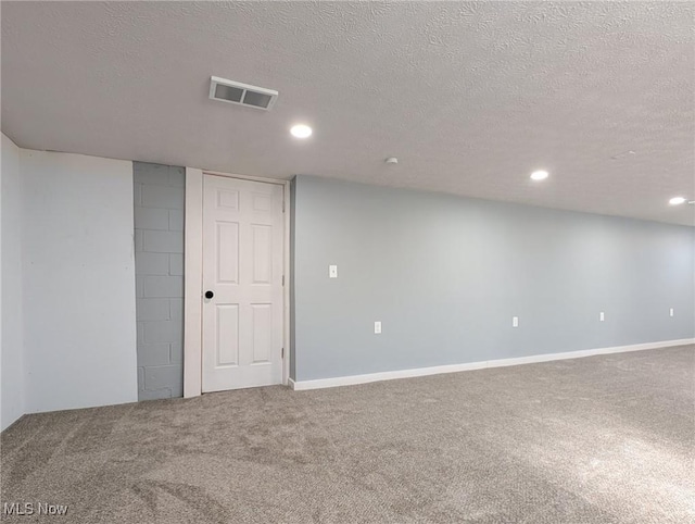 finished below grade area with visible vents, baseboards, carpet flooring, recessed lighting, and a textured ceiling