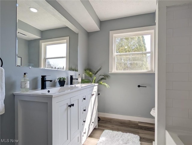 full bath with a wealth of natural light, wood finished floors, baseboards, and a sink