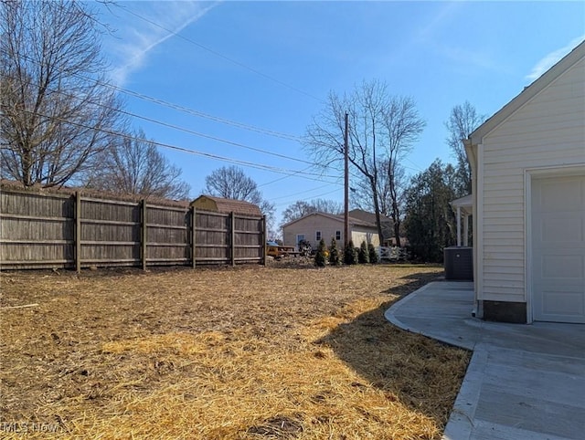 view of yard with central AC unit, fence, and a garage