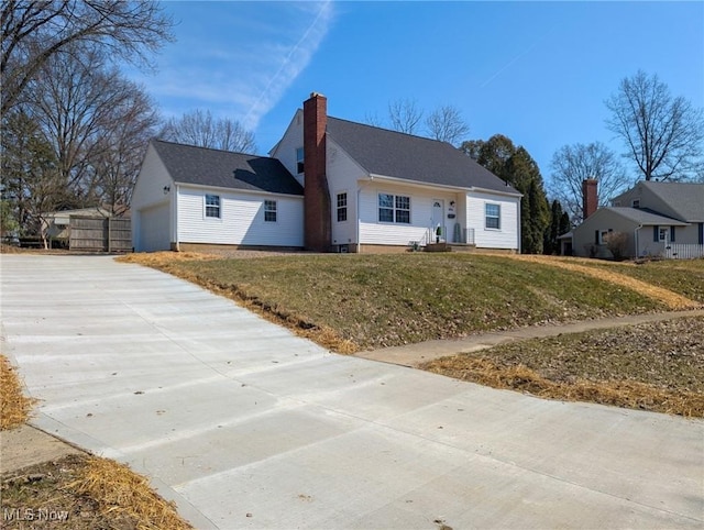 view of front of house featuring a front lawn, a chimney, and a garage