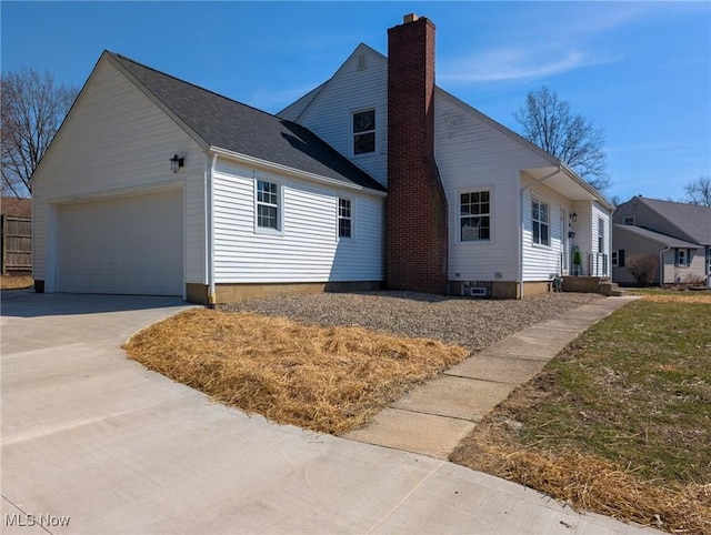 view of home's exterior featuring a garage, driveway, and a chimney