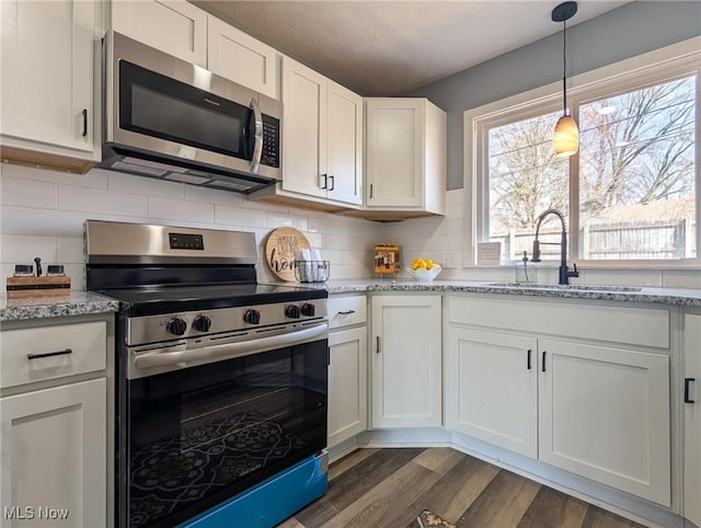 kitchen featuring a wealth of natural light, backsplash, appliances with stainless steel finishes, and a sink