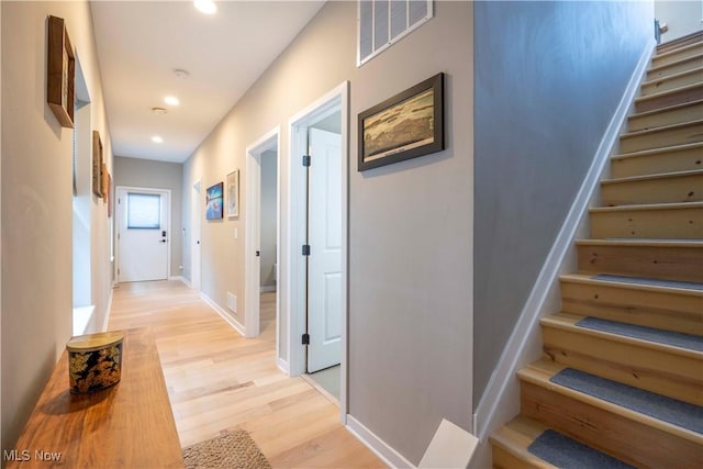 corridor featuring visible vents, light wood-style flooring, recessed lighting, baseboards, and stairs